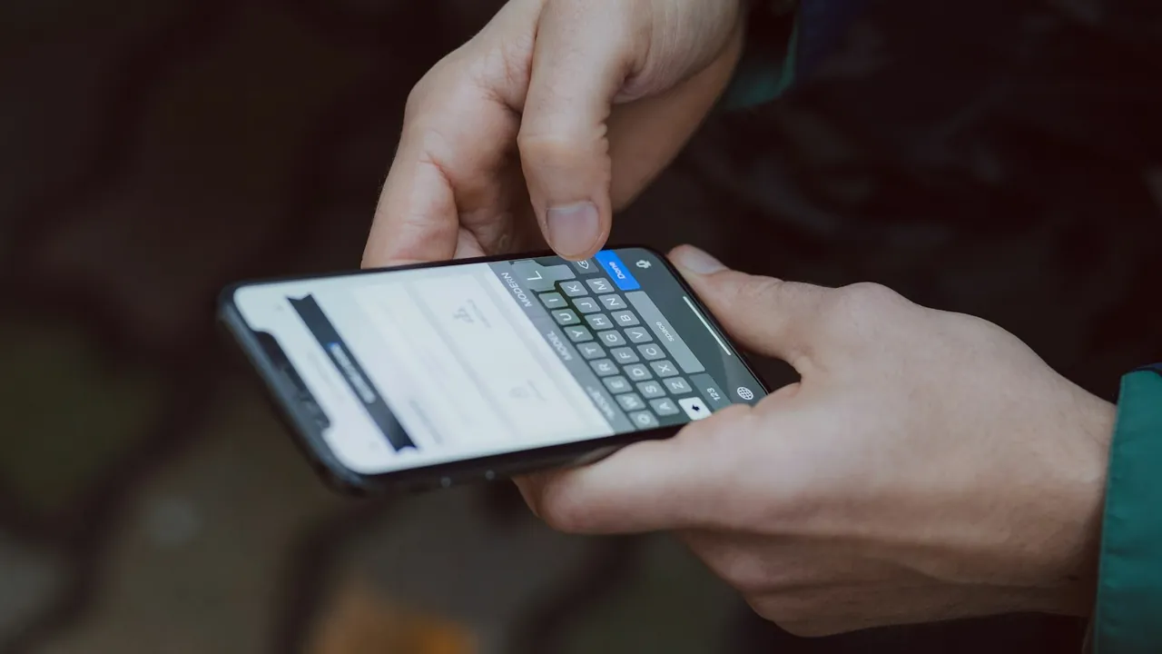 Two hands hold a smartphone and type a text message on its on-screen keyboard.
